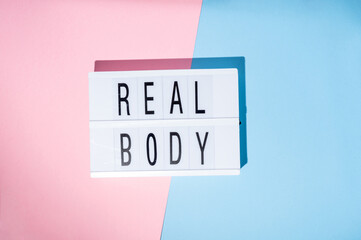 Real Body text on the lightbox. Concept of feminism on a blue and pink background. Top view