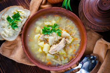 Buckwheat soup with meat in a clay bowl on the table.