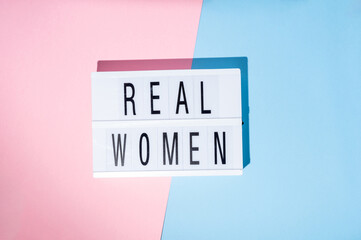 Real Women text on the lightbox. Concept of feminism on a blue and pink background. Top view