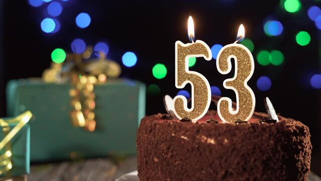 Birthday candle number fifty three on a sweet cake on the table, 53rd birthday. Fire from the lighter, blow out the holiday candle.