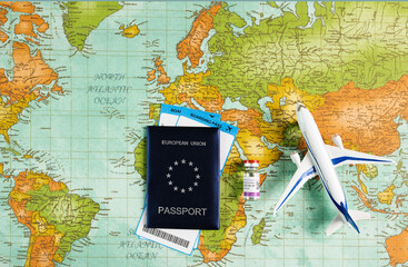 Safe travel during the pandemic, security checks at airports and borders. Concept of the EU health passport with airline tickets, coronavirus vaccine vial and model plane on a world map background.