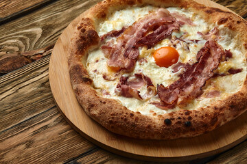 Carbonara pizza with bacon and egg on wooden background