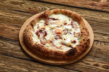 Carbonara pizza with bacon and egg on wooden background
