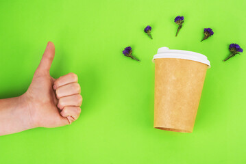 coffee cup with blue flowers in the up and hand of approval symbol on green background. zero waste concept