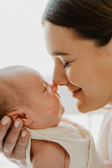 A young mother holds a newborn in her arms. Close-up photo.