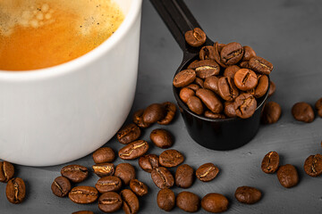 White cup of espresso coffee and coffee beans close-up. Coffee preparation.