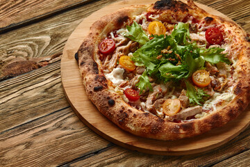 Pizza Caesar. Pizza with chicken, tomato, cheese and lettuce on wooden board. Top view. Free space for your text. Delivery food