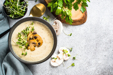 Mushroom soup on light stone table with herbs. Champignon cream soup. Top view with copy space.