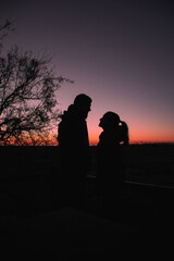 Fototapeta na wymiar Silhouette of a man and a woman enjoying sunrise on the beach
