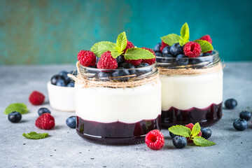 Parfait with cream or yogurt, jam and fresh berries in the glass jar. Close up. Healthy dessert or snack.