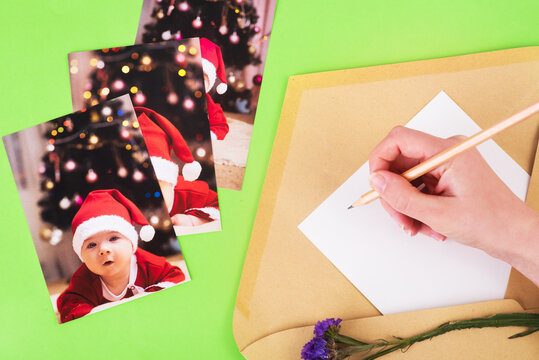 Christmas, New Year photos of a baby and writting hand in white paper in a postal envelope on a green background