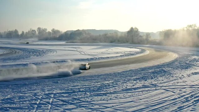 Slow motion aerial shots of winter drift competitions on the ice of a frozen lake.