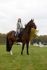 Beautiful young woman riding a horse on the field. Sideways to the camera. Freedom, joy, movement