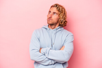 Young caucasian man isolated on pink background dreaming of achieving goals and purposes