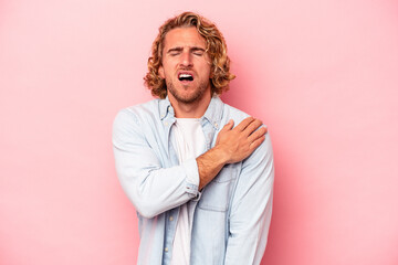 Young caucasian man isolated on pink background having a shoulder pain.