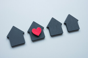House selection concept. Figurines of houses and one with a heart symbol as the chosen one.
