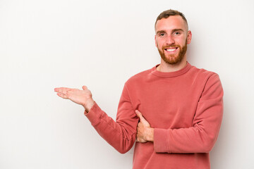 Young caucasian man isolated on white background showing a copy space on a palm and holding another hand on waist.