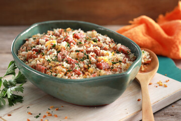 Tigela com farofa brasileira com arroz sobre mesa de madeira rústica