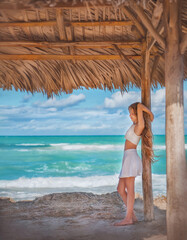 The girl stands on the shore of the Atlantic Ocean. Girl with long hair by the ocean. Beautiful...