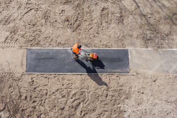 New asphalt construction worker laying road surface on walkway work tarmac. Sidewalk construction road ground work asphalt. Groundwork asphalt paving road worker with vibratory plate compactor rammer - obrazy, fototapety, plakaty