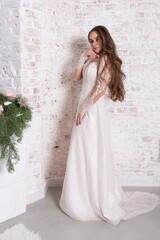 The bride in full growth, against the backdrop of a white brick wall.