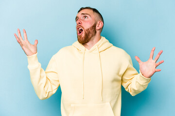 Naklejka premium Young caucasian man isolated on blue background screaming to the sky, looking up, frustrated.