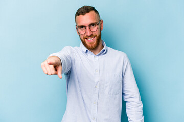 Fototapeta premium Young caucasian man isolated on blue background cheerful smiles pointing to front.