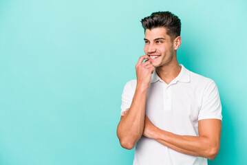 Young caucasian man isolated on blue background relaxed thinking about something looking at a copy space.