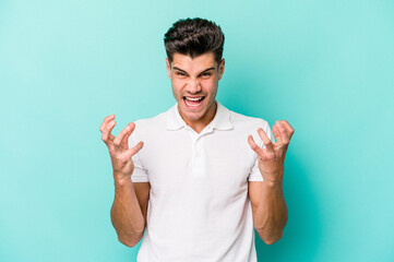 Young caucasian man isolated on blue background screaming with rage.