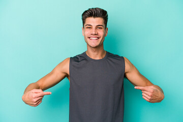 Fototapeta premium Young caucasian man isolated on blue background points down with fingers, positive feeling.