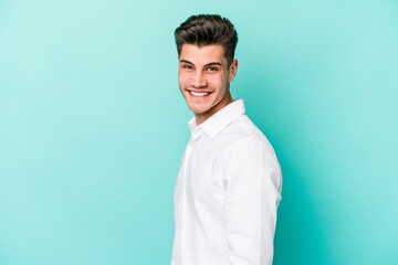 Young caucasian man isolated on blue background confident keeping hands on hips.