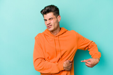 Young caucasian man isolated on blue background having a liver pain, stomach ache.
