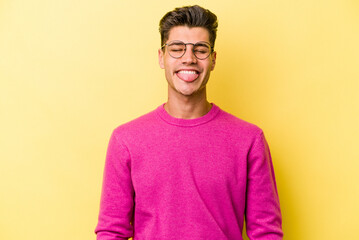 Young caucasian man isolated on yellow background funny and friendly sticking out tongue.