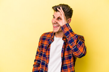 Young caucasian man isolated on yellow background excited keeping ok gesture on eye.