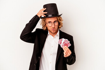 Young magician caucasian man holding magic cards isolated on white background being shocked, she has remembered important meeting.