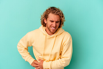 Young caucasian man isolated on blue background having a liver pain, stomach ache.
