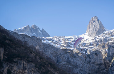 parachuter flying with  his parachute over snowy mountains