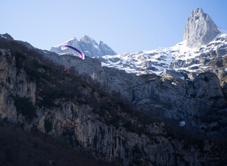 parachuter flying with  his parachute over snowy mountains