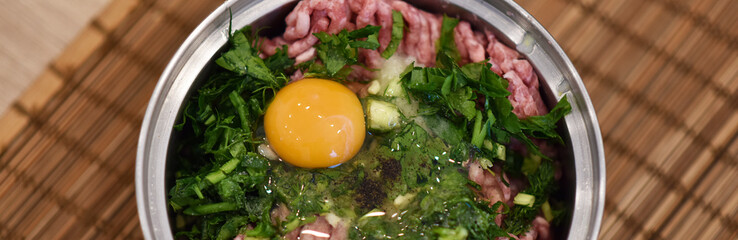 minced meat with herbs and raw egg in a stainless steel saucepan