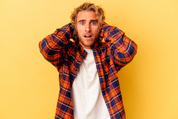 Young caucasian man isolated on yellow background screaming with rage.