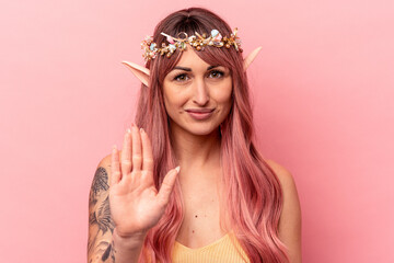 Young caucasian elf woman isolated on pink background standing with outstretched hand showing stop sign, preventing you.