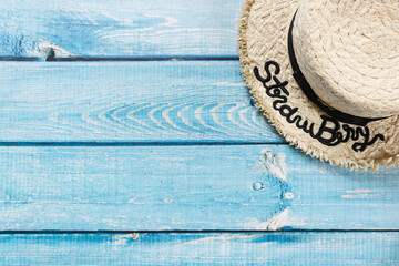 Fototapeta na wymiar A straw hat on light blue wooden background, beach and Summer concept.