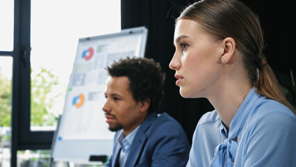 Fototapeta premium young businesswoman near blurred african american colleague in meeting room