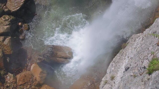 Waterfall crashing onto the rocks in the river. Slow motion, high angle view, arc shot. 