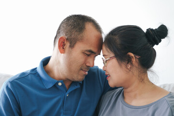 Portrait of Asian mature couple sitting in the living room. wife and husband hugging, holding hand with happiness and cheerful. Love, safety, and insurance family concept.