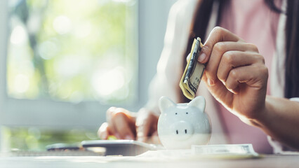 Closeup of businesswoman hand putting money banknote into piggy bank for saving money. saving money...