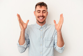 Fototapeta premium Young caucasian man isolated on white background smiling and showing a heart shape with hands.