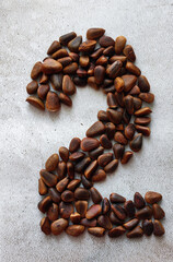 number two consists of large brown pine nuts on a background of gray marble created from natural...