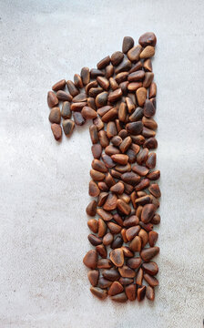 number one consists of large brown pine nuts on a background of gray marble, created from natural materials