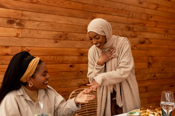 Modest muslim woman showing her engagement ring to her friend in a cafe